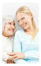 elderly woman and her caregiver smiling while looking at each other